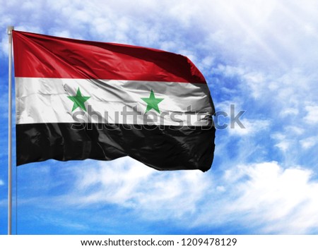 National flag of Syria on a flagpole in front of blue sky