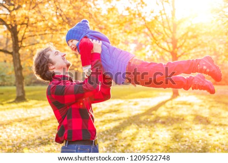 Child and father in autumn park. Happy adorable boy with dad fall leaves. The concept of childhood, family and kid laughs outdoors. 