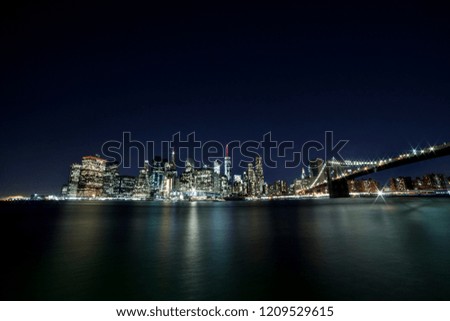 View of Lower Manhattan Skyline form Brooklyn Bridge Park at night. Brooklyn Bridge on the right