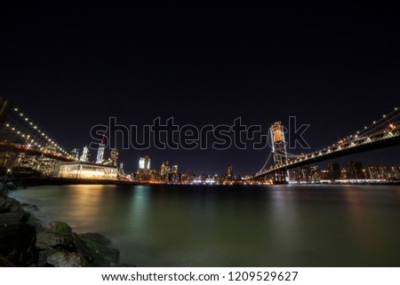 View of Manhattan Skyline form Brooklyn Bridge Park at night. Brooklyn Bridge on the left and Manhattan bridge on the right