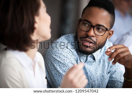 Close up of multiracial colleagues chat talking or discussing something in office, black man speak with female coworker negotiating about business project, having conversation. Cooperation concept Royalty-Free Stock Photo #1209547042