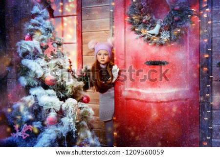 Pretty child girl is standing near her house decorated for Christmas. Merry Christmas and Happy New Year.