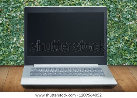 Computer notebook blank screen for advertising on nature green leaf background. Selective focus.