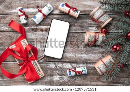 Xmas background of old wood. Christmas tree with American and European money. Holiday Gifts. Top view. Space for text on the phone.