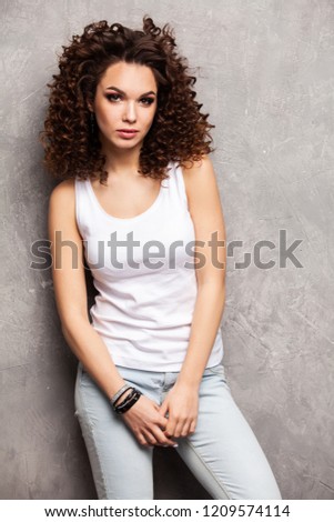 Image of happy young woman standing isolated over gray background. Looking camera pointing.