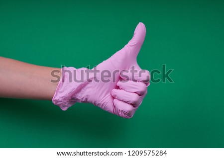 hand in pink glove on green background