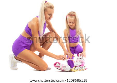 Family, mother and daughter, posing in studio wearing inline rollerskates