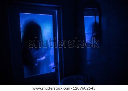 Horror silhouette of woman in window. Scary halloween concept Blurred silhouette of witch in bathroom