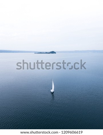 peaceful scene of a sail boat crossing a lake in an autumn moody day