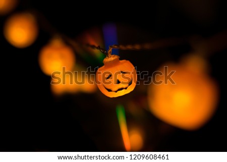Halloween orange carved pumpkin garland glowing in the dark with brurred elements and . Mystical and spooky holiday concept.