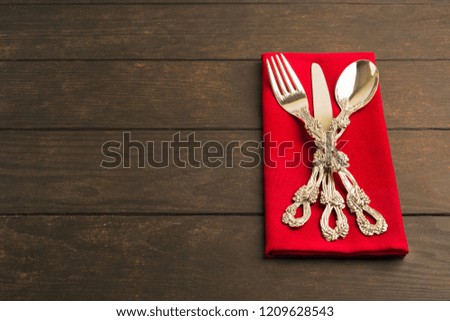 Set of tableware on red tissue over wooden table with copy space