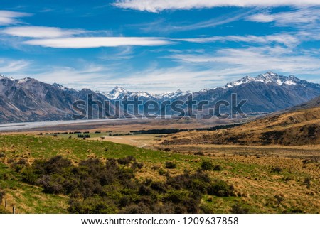 Photo looking over a valley surrounded by snow-capped mountains in New Zealand. Royalty-Free Stock Photo #1209637858