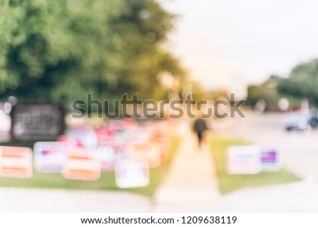 Motion blurred people walking on residential street near yard sign at for primary election day in Dallas, Texas, USA. Signs greeting early voters.