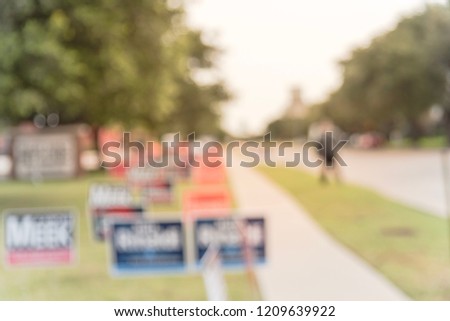Motion blurred people walking on residential street near yard sign at for primary election day in Dallas, Texas, USA. Signs greeting early voters.