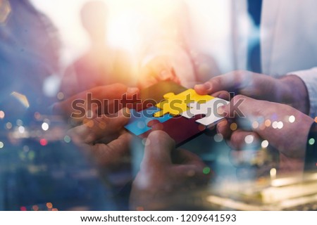 Business people join puzzle pieces in office. Concept of teamwork and partnership. double exposure with light effects Royalty-Free Stock Photo #1209641593