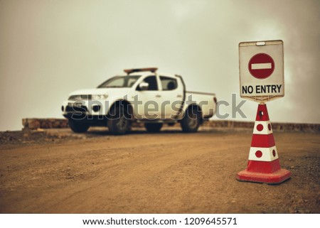 sign No Entry or Do not enter on mountains road with SUV on background