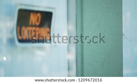 Defocused close up of No Loitering sign in store window