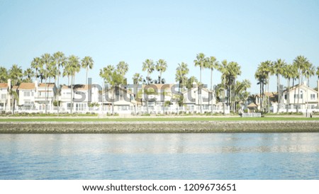 Wide shot of oceanfront homes and palm trees under a sunny sky