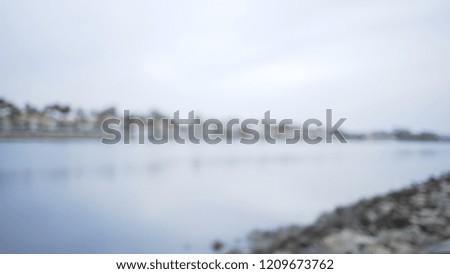 Blurred side view of suburban skyline along bay from rocky coast