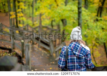 woman walking on trail in porcupine mountain state park in autumn with camera over shoulder