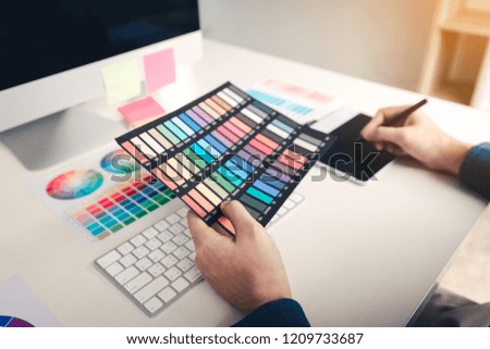Graphic designer using digital graphics tablet and looking color.