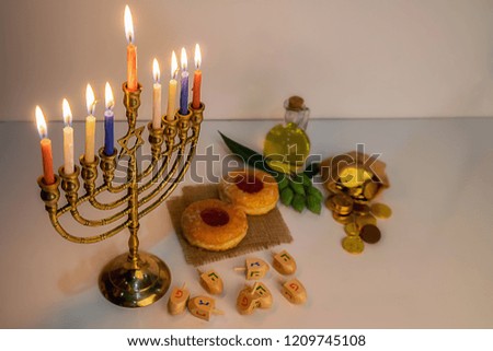 Jewish holiday hanukkah celebration with menorah (traditional candelabra), wooden dreidels (spinning top), donut, olive oil and chocolate coins on white table. table. table.