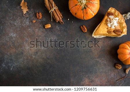 Pumpkin Pie with whipped cream, pecan nut and cinnamon on rustic background, top view, copy space. Homemade autumn pastry for Thanksgiving - piece of pumpkin pie.