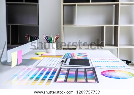 Modern office workplace with tablet, Graphic designer and color swatch samples at workplace.
