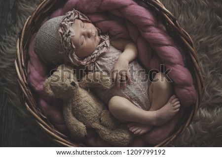 newborn girl in a basket with a teddy bear, taking pictures of newborns, concept of calm childhood and sweet dream
