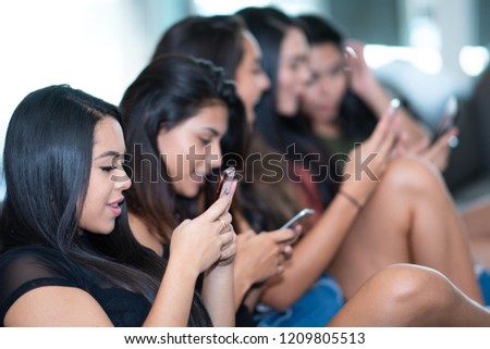 Group of five teen girls using their smart phones