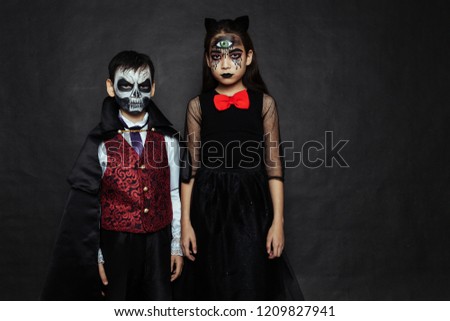 Children in carnival costumes with scary face painting on Halloween. Black background