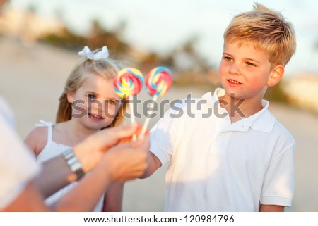 Cute Brother and Sister Picking out Lollipop from Their Mom at the Beach.
