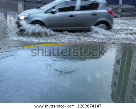 Blurred car driving on flooded street and splashing water
