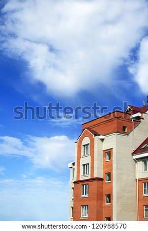 Photo of white-red brick house with red roof against beautiful sky