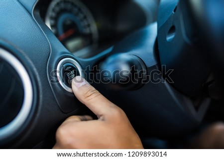Finger of man press start button engine of car red color with silver and black color interior of car