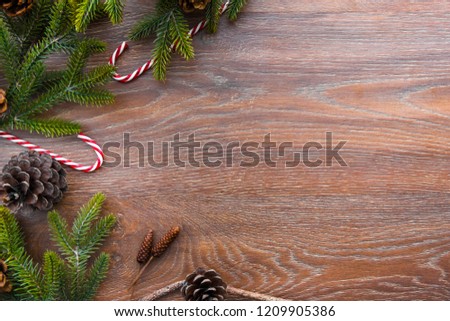 Christmas composition background on wood table with pine branches with cones and candy canes. Top view with copy space, flat lay.