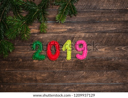 2019 made of felt and Christmas fir tree branch. Childish craft New year background on dark rustic wooden background. Holiday card - 2019 happy new year!