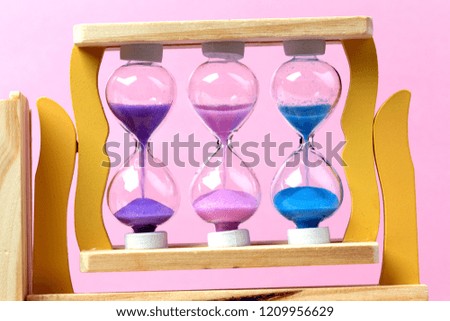 colored hourglass on pink wall background