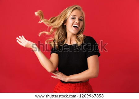Portrait of optimistic blond woman 20s smiling at camera with blowing hair isolated over red background in studio