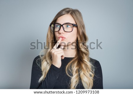 beautiful blonde woman thinks wearing glasses isolated over gray background