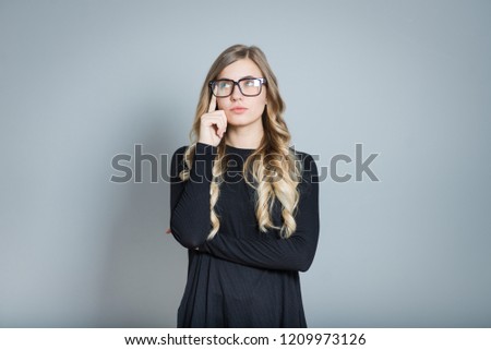 beautiful blonde woman thinks wearing glasses isolated over gray background