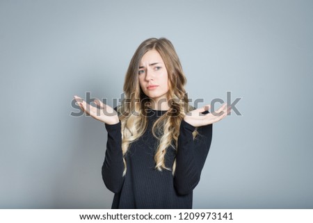 beautiful blonde woman compares the options, can not choose, isolated over a gray background