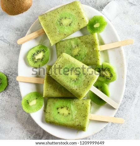 Popsicles from kiwi on plate over stone background. Top view, flat lay