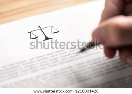 Attorney, lawyer, solicitor or jurist working on a business brief in law firm. Legal contract, clause or article paper. Man writing document with scale icon and sign with pen. Judge making decision.