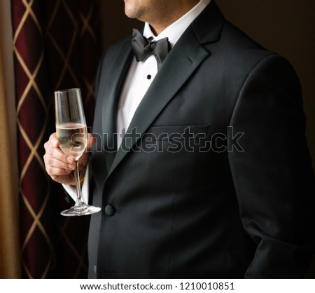 Groom posing for pictures holding his drink