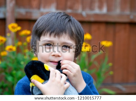 Portrait cute little boy with a happy face playing with penguin soft toy,Happy child having fun playing outdoors in the garden.