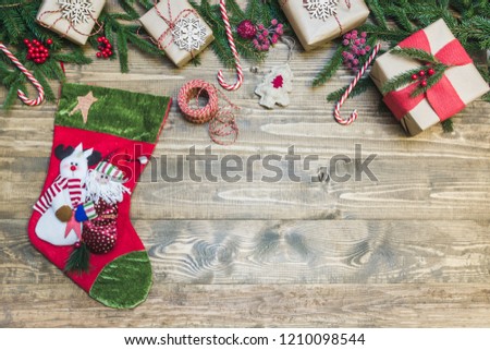 Christmas holiday frame - sock, tree, gifts, holly berries and decoration on wooden board. Holiday banner. Top view.