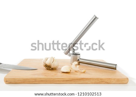 Garlic Press and Garlic on Wooden Plate
