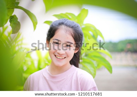 Beautiful Asian girl standing outdoors and looking at camera look happy.