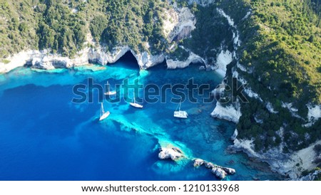 Aerial drone bird's eye view photo of yachts in tropical rocky bay with turquoise clear waters and deep turquoise sea caves in popular mediterranean destination